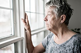 Sad senior woman looking out the window