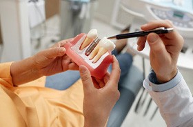 Dentist using model to explain dental implants during consultation