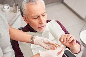Senior man talking with dental team member about dentures