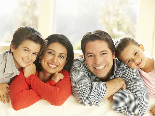 Smiling mother father and two kids sitting on couch