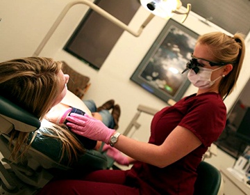 Dentist smiling at patient while providing treatment