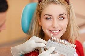 Woman's smile compared with tooth color chart