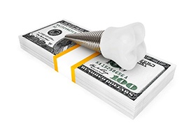 Dental implant on money stack representing the cost of dental implants in Buzzards Bay
