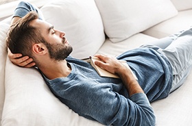 Man napping with head propped up on pillows