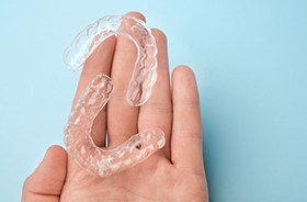 Two clear aligners resting on person’s palm