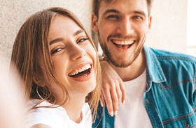 Couple with healthy teeth taking selfie, not worried about dental emergencies