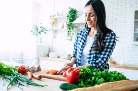 Woman chopping vegetables, preparing a healthy meal for herself