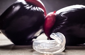 Sports mouthguard in foreground, boxing gloves in background