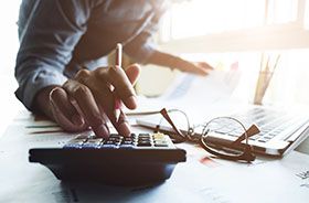 Person using calculator to budget for the cost of root canal therapy in Buzzards Bay