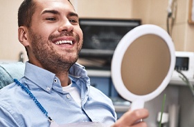 Man admiring his smile after receiving tooth-colored fillings