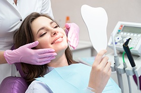 Happy dental patient looking into hand mirror