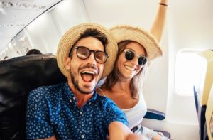 Happy young couple taking selfie on airplane