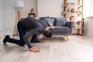 Man looking under sofa, searching for lost Invisalign aligner