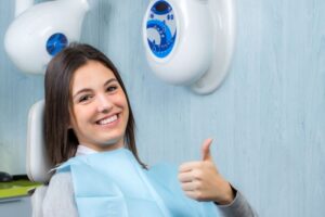 Teeth whitening patient making thumbs-up gesture 